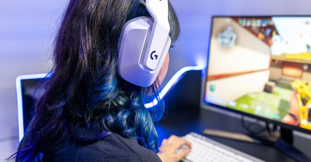 A young gamer playing an online game while wearing headphones, focused on the screen.